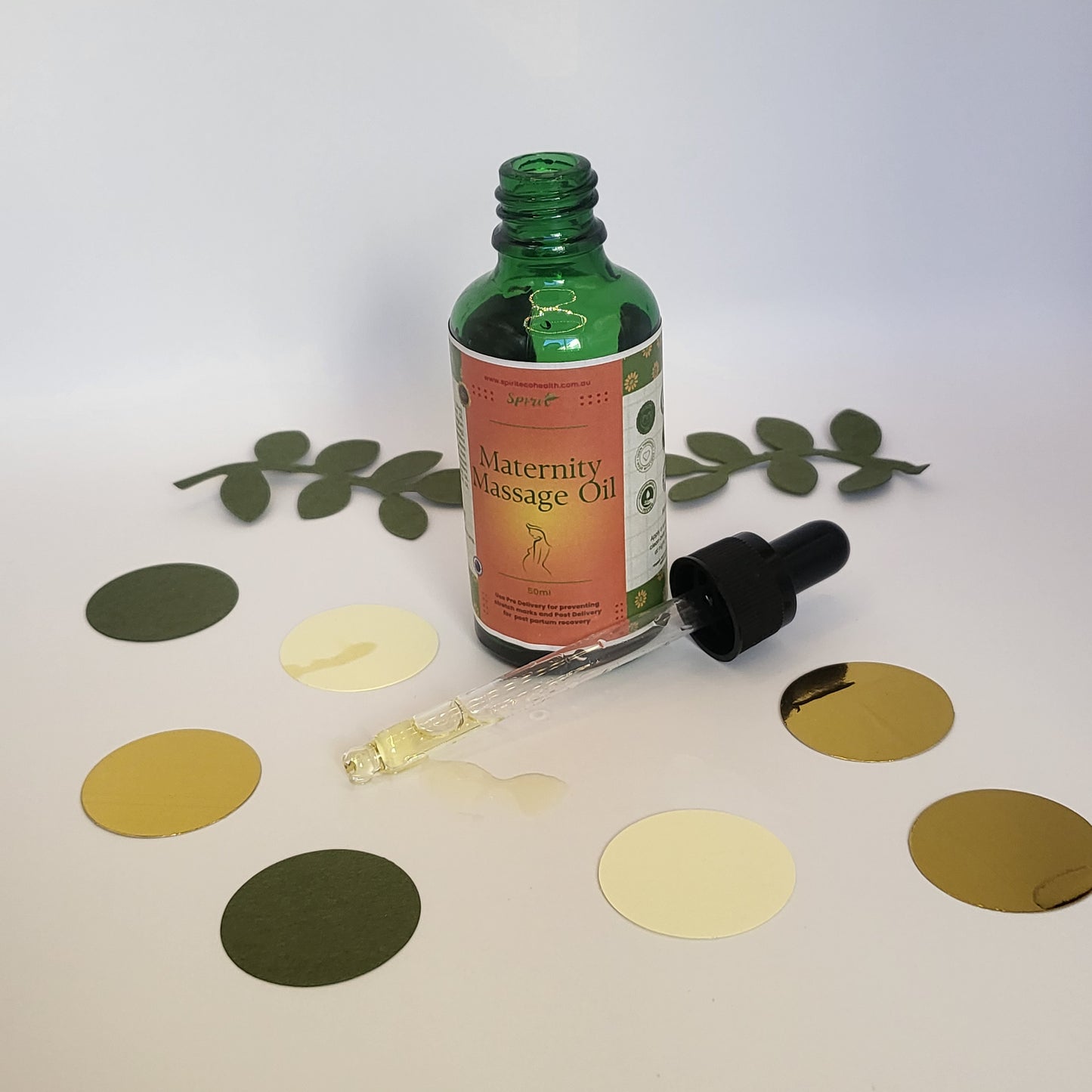 Spirit Belly anti stretch mark oil next to green and golden confetti